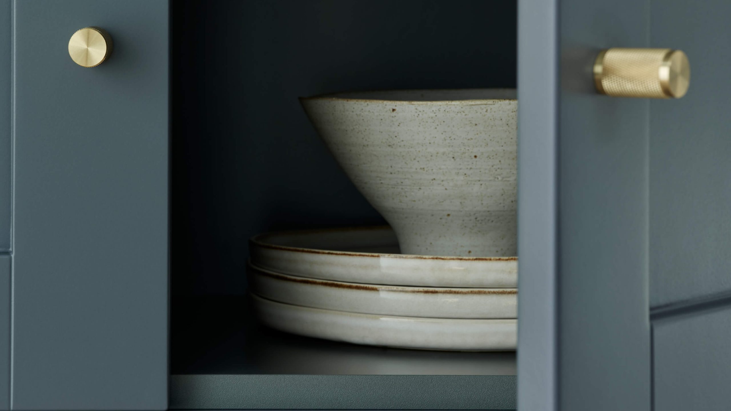 Öppnat skåp i blå ramlucka med ljus keramik inuti